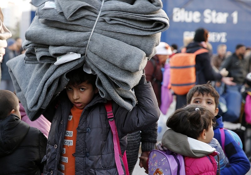 A migrant child carries blankets as refugees and migrants disembark from the passenger ferry Blue Star1 at the port of Piraeus, near Athens, Greece, January 31, 2016. (Reuters Photo)