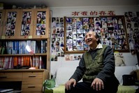 This photo taken on Dec. 17, 2019 shows matchmaker Zhu Fang smiling at his house with walls covered with images of single women who have come to him over the years in Beijing. (AFP Photo)