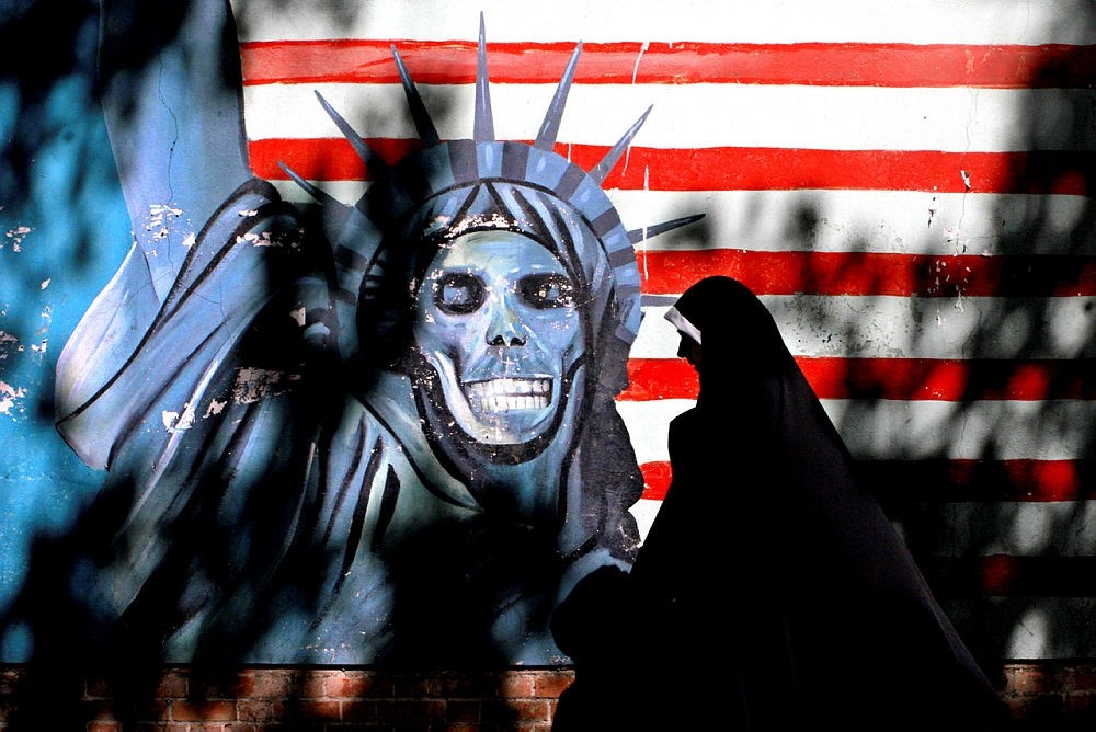 Iranian woman walks past graffiti art characterizing the U.S. Statue of Liberty, painted on the wall of the former U.S. Embassy in Tehran, Iran. (AP Photo)