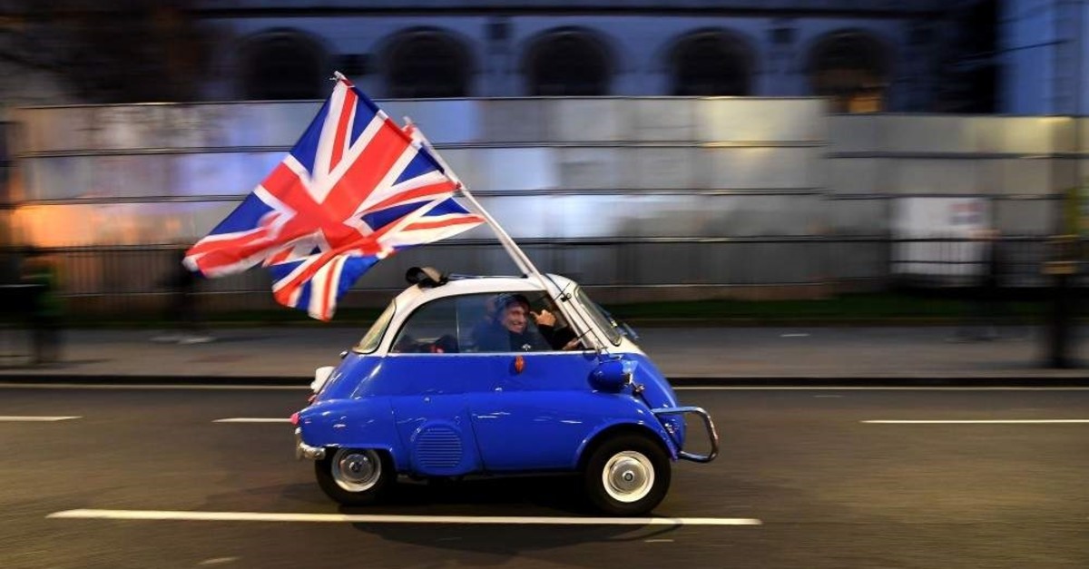 A man waves Union flags from a small car as he drives past Brexit supporters gathering in Parliament Square, central London, Jan. 31, 2020, the day that the U.K. formally left the EU. (AFP Photo)