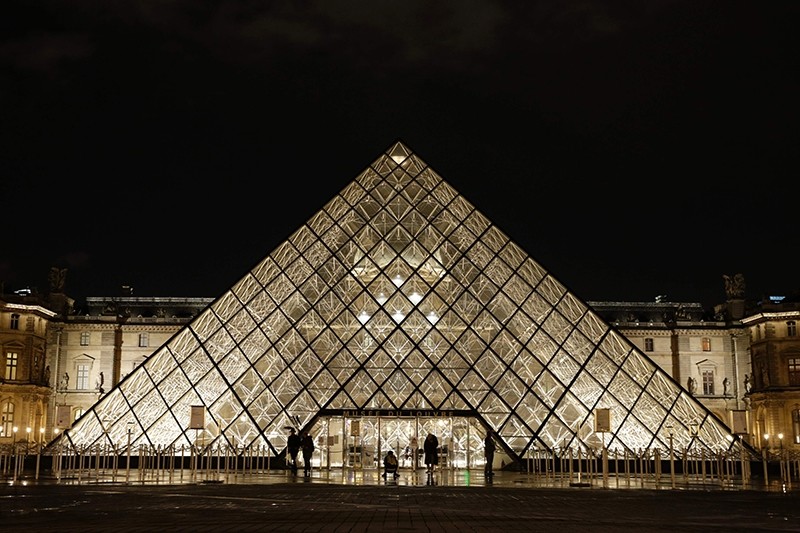 People stand outside the Louvre Pyramid of the Louvre museum at night on February 3, 2017, in Paris. (AFP Photo)