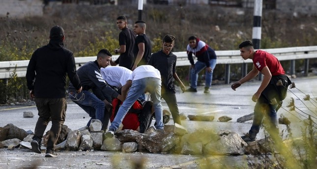 شبان فلسطينيون ينقلون متظاهراً أصيب برصاص جيش الاحتلال الإسرائيلي عند المدخل الشمالي لمدينة رام الله بالضفة الغربية، 14 أكتوبر  2022 AFP