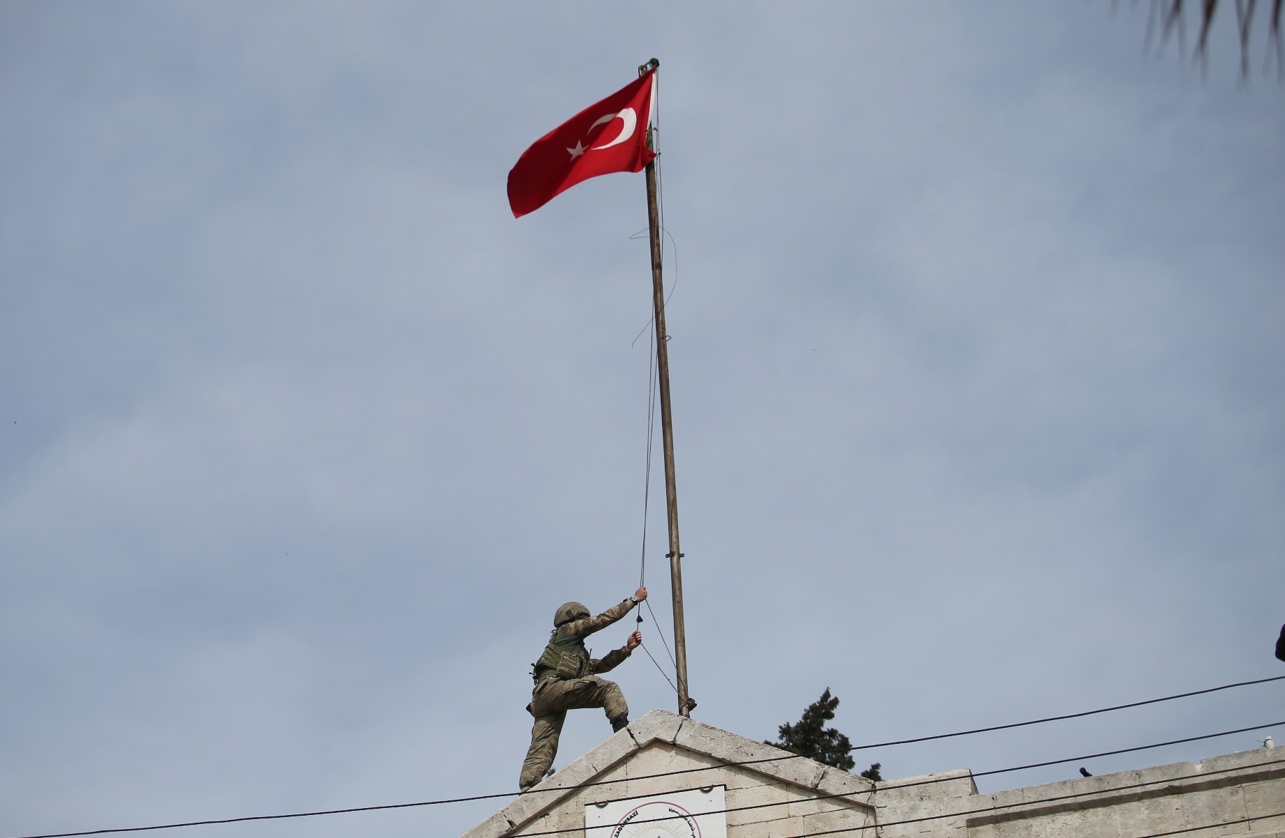 A Turkish soldier hoists the Turkish national flag on a building after after it was liberated from YPG terrorists as part of Operation Olive Branch, March 18. 