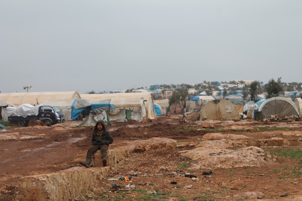 A boy sits on a rock at the Atmeh Refugee Camp. (Photos by Ayu015fe Betu00fcl Bal)
