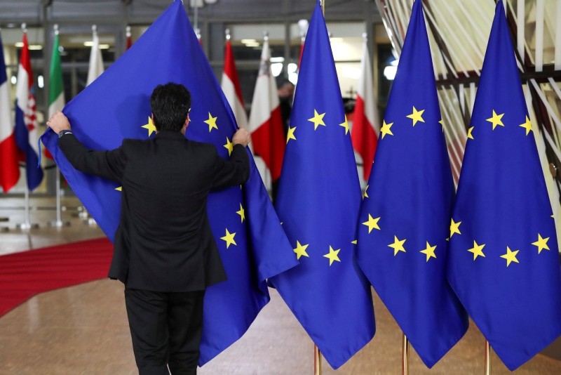 A staff member adjusts flags prior to the extraordinary EU leaders summit to finalize and formalize the Brexit agreement with the UK in Brussels, Belgium, Nov. 25, 2018. (Reuters Photo)