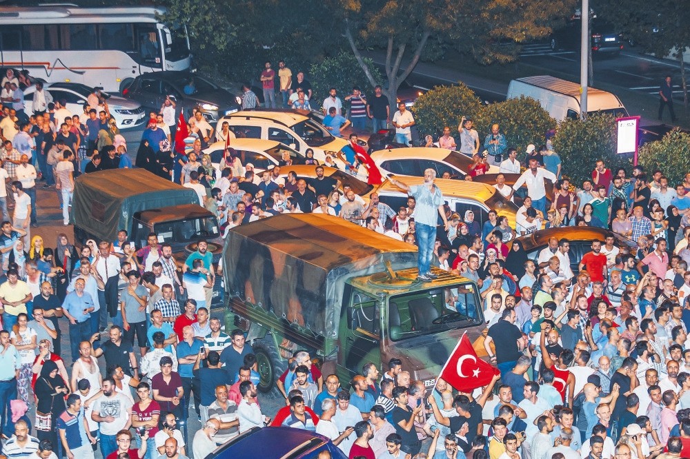 People surround military trucks of putschist troops on July 15, 2016, outside AK Party offices in Istanbul during the coup attempt. Fifteen putschists involved in the takeover of the offices were sentenced to life yesterday.