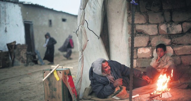 A Palestinian man and his son warm themselves during cold, rainy weather in a slum on the outskirts of the Khan Younis refugee camp, southern Gaza Strip, Jan. 5.