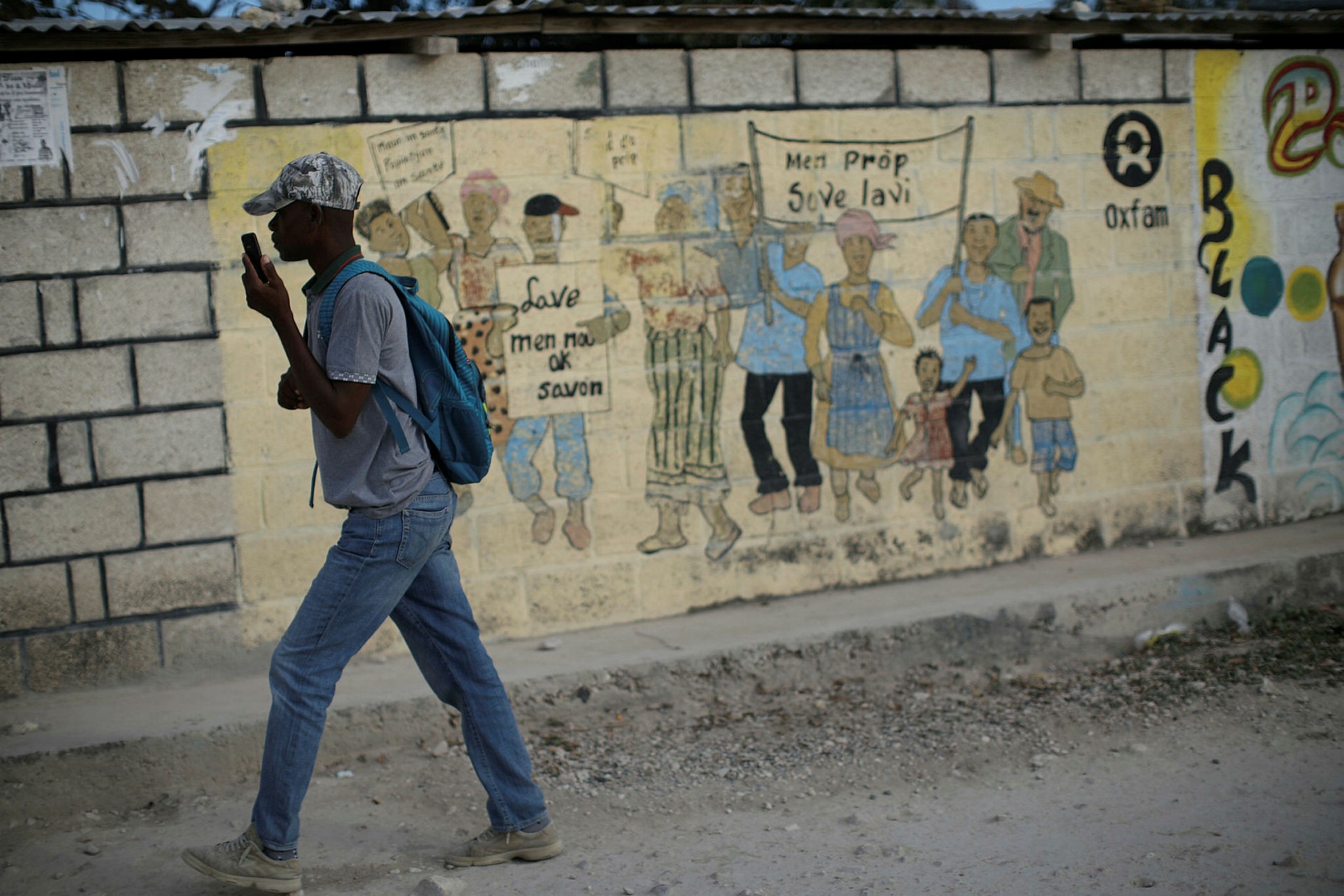 A man walks past an Oxfam sign in Corail, a camp for displaced people of the 2010 earthquake, Haiti, Feb. 13.