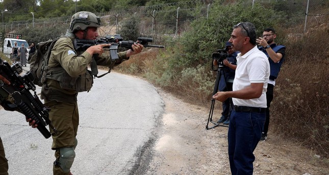 أحد جنود جيش الاحتلال الإسرائيلي يوجه بندقيته في وجه فلسطيني وسط الضفة الغربية بعد استشهاد شاب فلسطيني برصاص الاحتلال، 10-7-2023  صورة: الأناضول