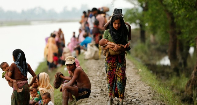 A Rohingya refugee woman with her child walks on a muddy path after crossing the Bangladesh-Myanmar border in Teknaf, Bangladesh, Sept. 7.