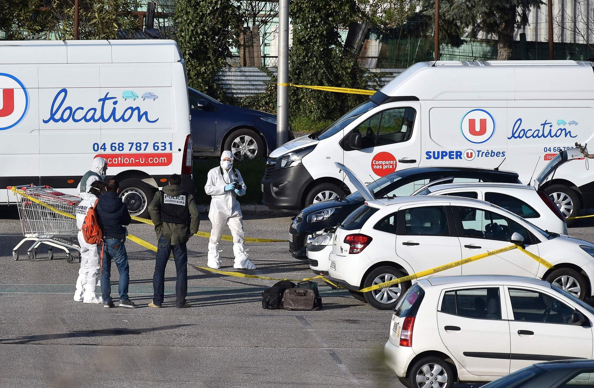 French forensic officers arrive to inspect a vehicle (C hood up) believed to belong to the hostage taker and parked outside the Super U supermarket in the town of Trebes, southern France on March 23, 2018. (AFP Photo)