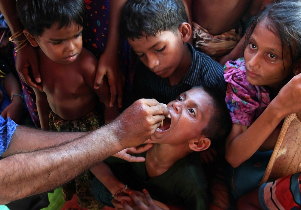 Rohingya refugee children look on as a Bangladeshi volunteer administers an oral cholera vaccine at the Thankhali refugee camp in Ukhia district, Oct. 10.