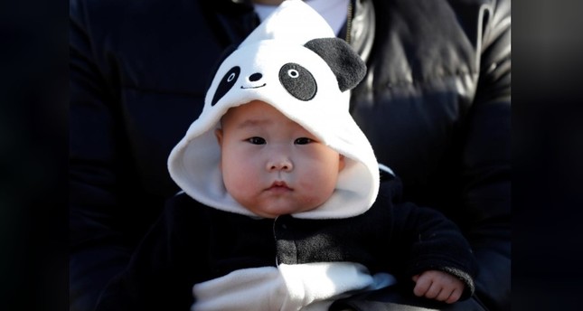 A baby wearing a costume featuring giant panda waits for starting the public debut of female baby panda Xiang Xiang, born from mother panda Shin Shin on June 12, 2017. (REUTERS Photo)