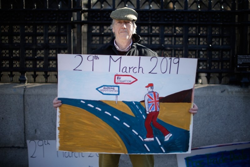 A leave the European Union supporter who didn't want to give his name poses for photographs outside the Houses of Parliament in London, Thursday, Feb. 14, 2019. (AP Photo)