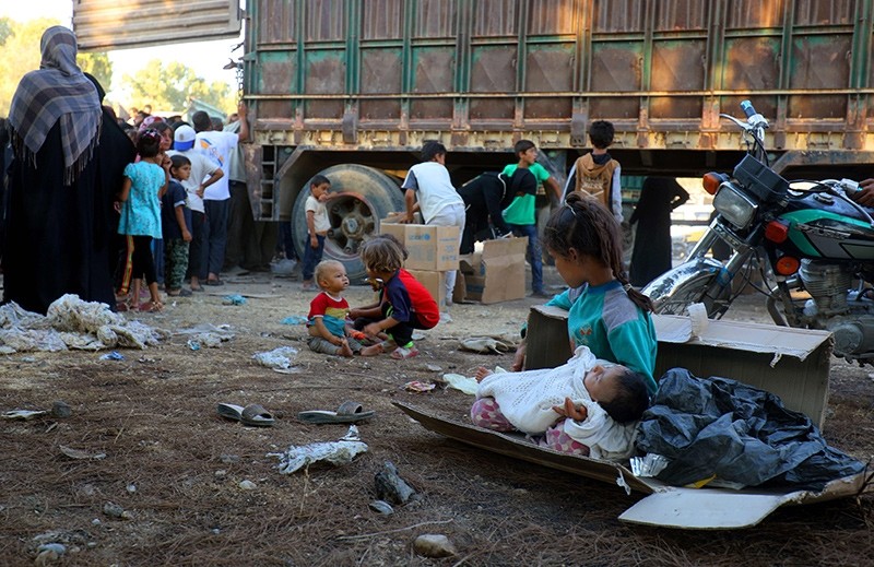 A picture taken on August 4, 2017 shows displaced Syrian children, who fled from Daesh's Syrian stronghold of Raqqa, receiving humanitarian aid delivered by UNICEF at a temporary camp (AFP Photo)