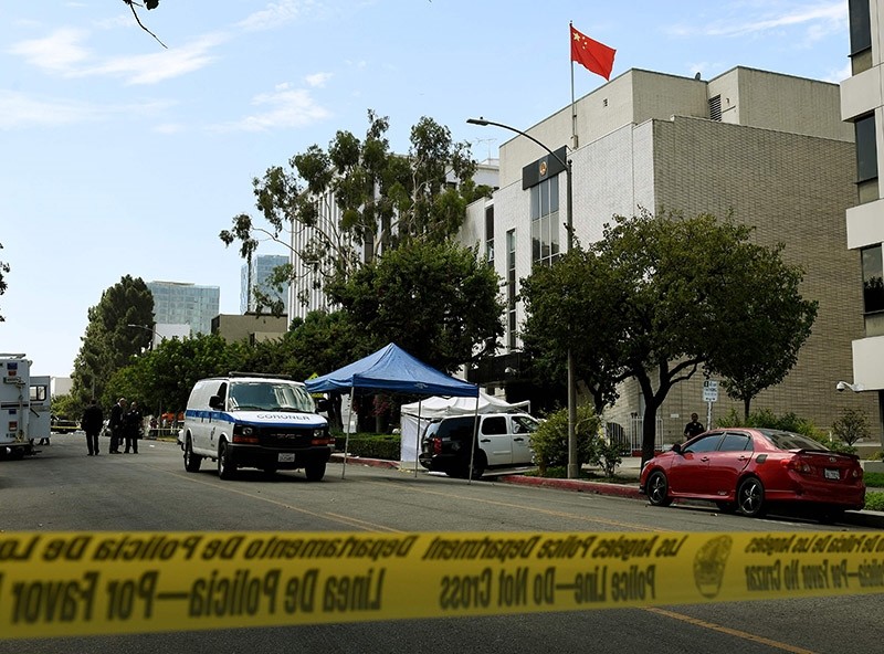 Staff from the Coroners office remove the body from the front of the Chinese Consulate (R) after a man of Chinese descent fired several shots at the consulate building then committed suicide near it's entrance, in Los Angeles (AFP Photo)