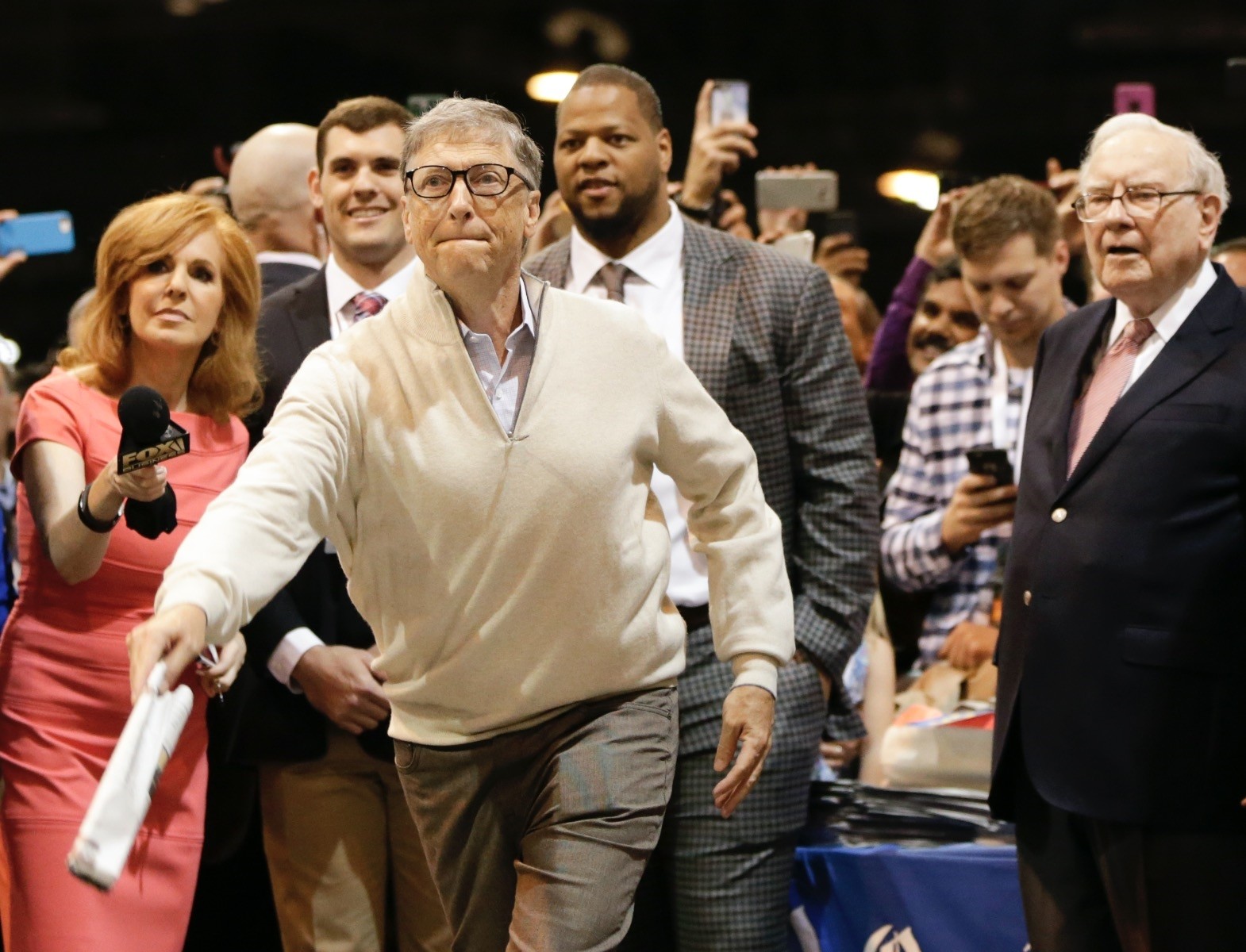 Bill Gates, a director with Berkshire Hathaway, is watched by Warren Buffett,right, Ndamukong Suh of the Miami Dolphine, second right, Taylor Martinez, second left, as he tries his hand at newspaper tossing competition at CenturyLink Center in Omaha.