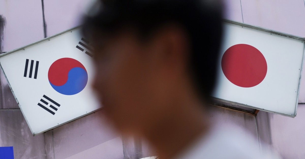 A man walks past an advertisement featuring Japanese and South Korean flags at a shop in the Shin Okubo area, known for Korean restaurants and stores selling K-pop merchandise, Tokyo, Aug. 13, 2019.