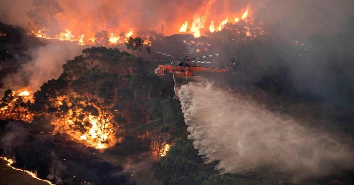 A handout photo taken and received on Dec. 31, 2019, from the State Government of Victoria shows a helicopter fighting a bushfire near Bairnsdale in Victoria's East Gippsland region. (AFP Photo/ State Government of Victoria)
