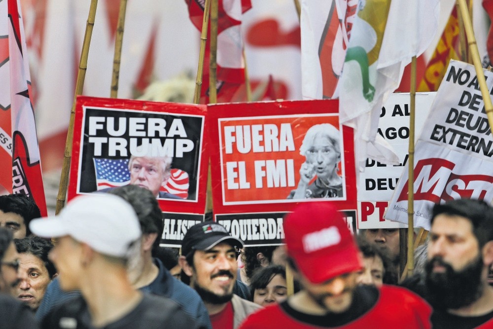 Protesters with signs bearing the faces of President Donald Trump and IMF chief Christine Lagarde march against the G20 summit being held in Buenos Aires, Argentina, Nov. 30.