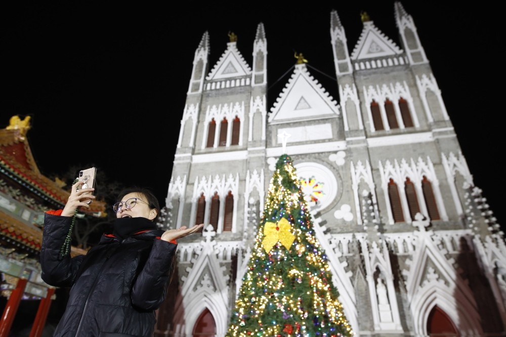 A woman takes photo in front of the Xishiku Catholic Church in Beijing, China, yesterday.