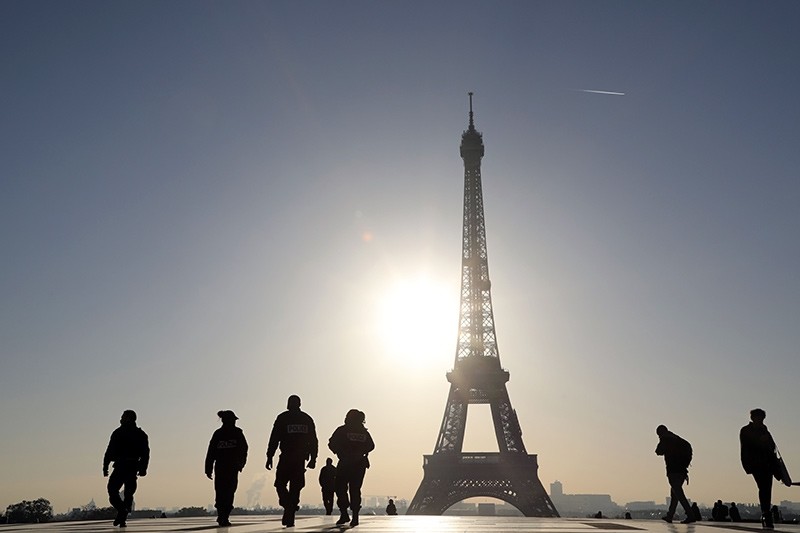 French police officers (L) patrol across the Trocadero plaza opposite the Eiffel Tower, at sunrise on November 7, 2017 in Paris (AFP Photo)