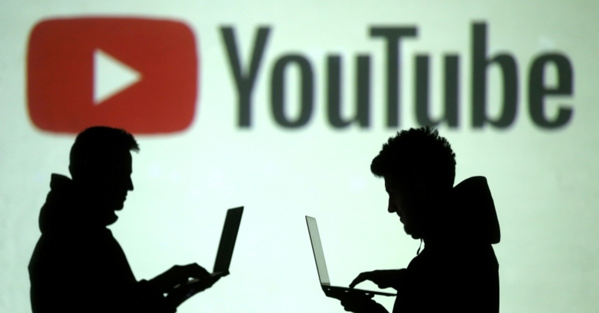 Silhouettes of mobile device users are seen next to a screen projection of Youtube logo in this picture illustration taken March 28, 2018. (REUTERS Photo) 