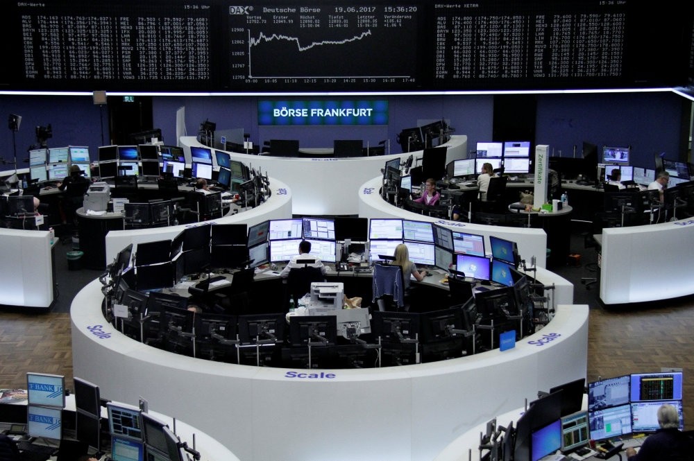 Traders work in front of the German share price index, DAX board, at the stock exchange in Frankfurt.
