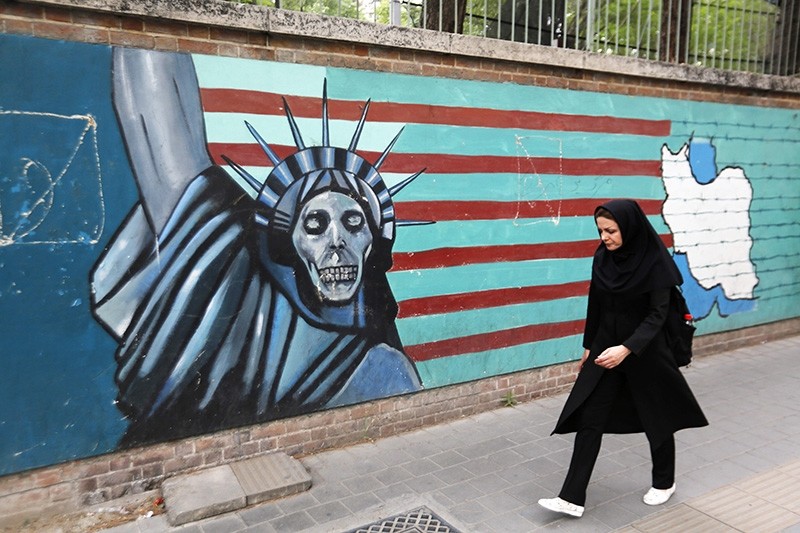 An Iranian woman walks past a mural on the wall of the former US embassy in the Iranian capital Tehran on May 8, 2018. (AFP Photo)