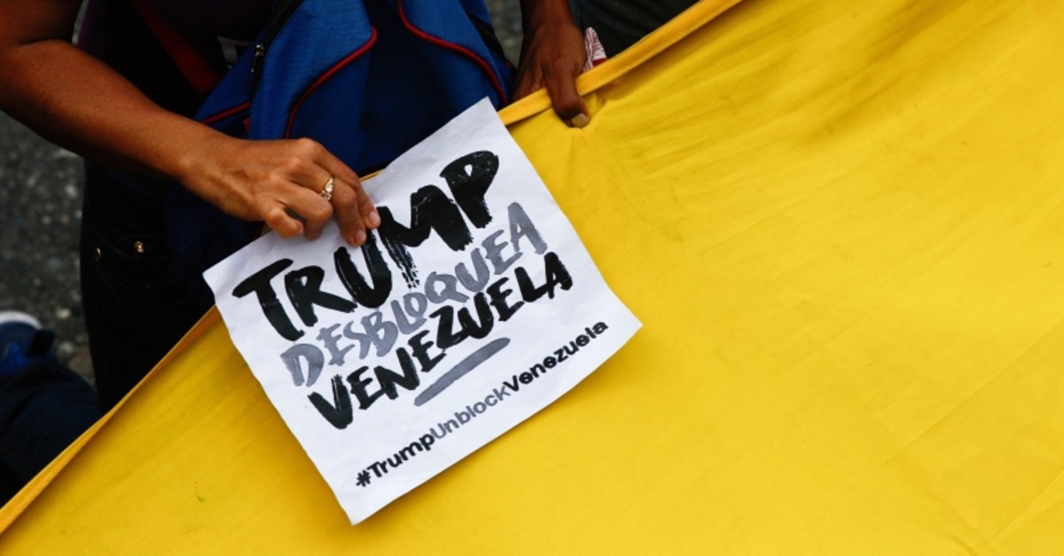 A government supporter holds a sign with a message that reads in Spanish: ,Trump unblock Venezuela, during a protest against U.S. sanctions, in Caracas, Venezuela, Wednesday, Aug. 7, 2019. (AP Photo)