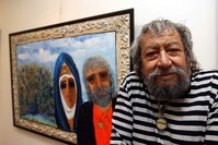 Fikret Otyam poses in front of one of his paintings. 