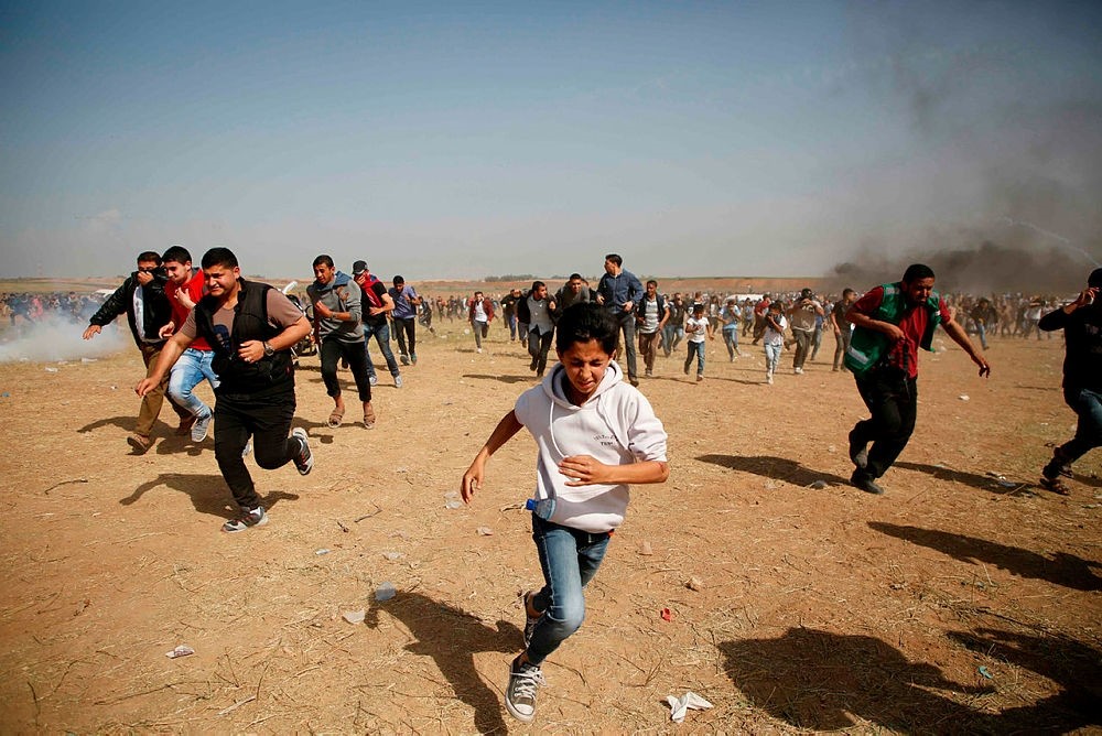 Palestinians run for cover from tears gas fired by Israeli security forces at a protest on the Israel-Gaza border east of the Jabalia refugee camp in the northern Gaza Strip on April 6, 2018. (AFP Photo)
