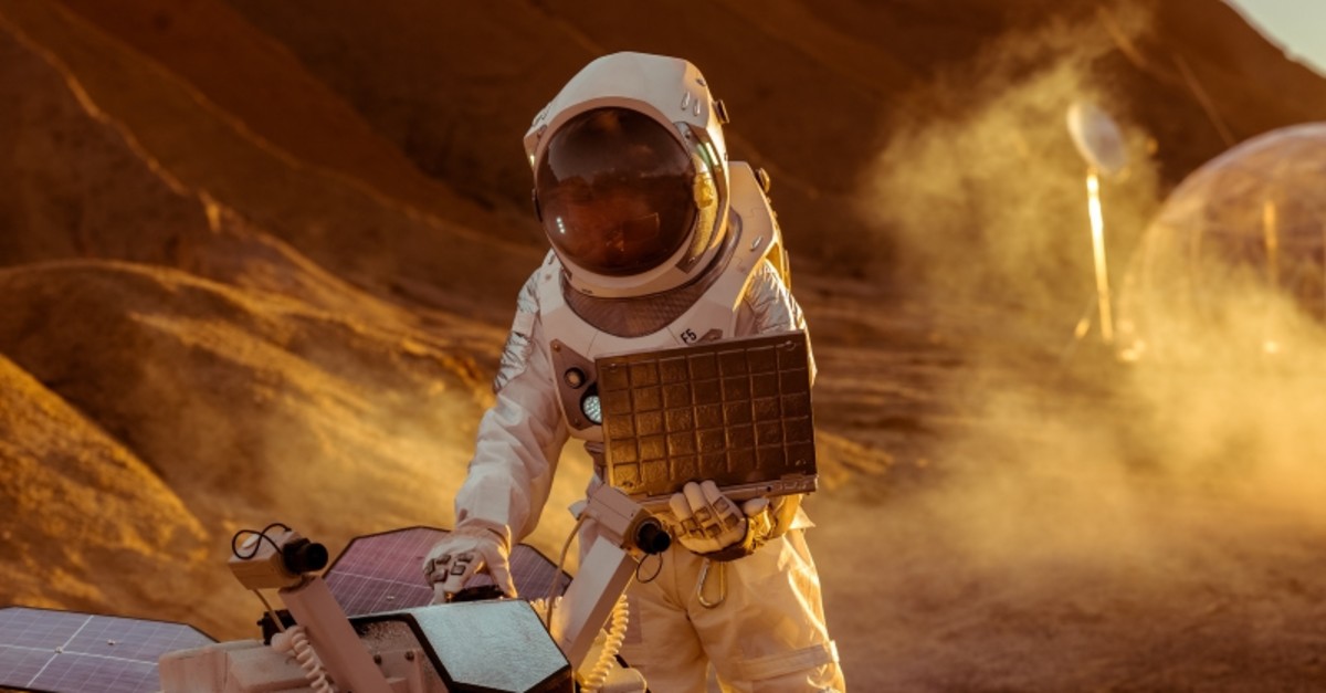 Astronaut in a space suit works on laptop, adjusting rover for Mars. (GETTY IMAGES/ iStock Photo)
