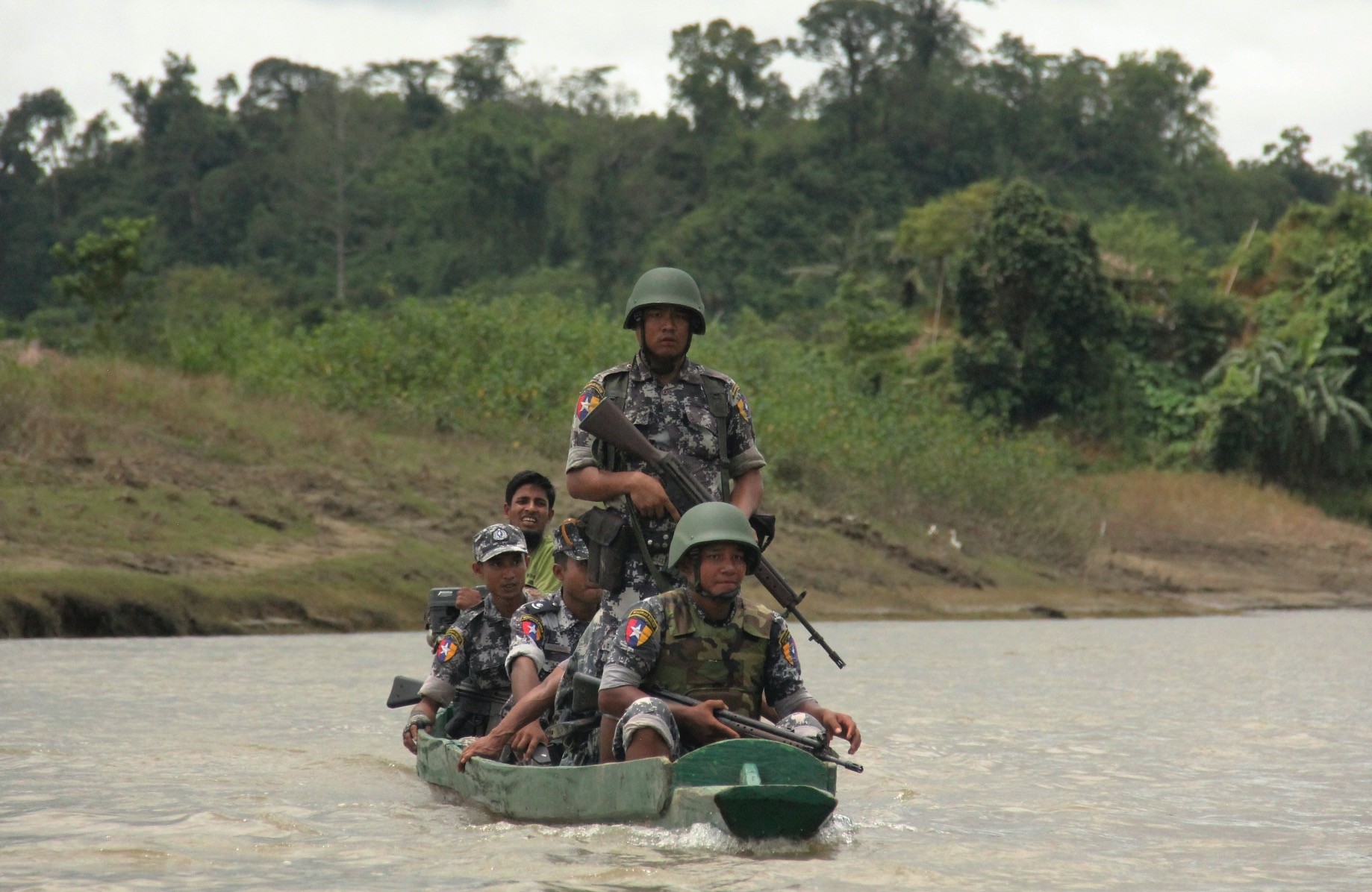 Myanmar Border Guard Police officers travel in a wooden boat at the Tin May village, Myanmar, July 14. 