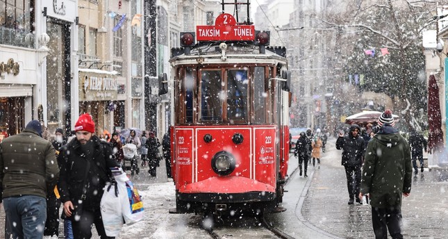 أشخاص يسيرون في شارع الاستقلال وسط تساقط الثلوج، إسطنبول، تركيا، 13-3-2022 صورة: الأناضول