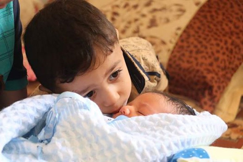 Waleed's older brother Mutasim, who survived a collapsing building in his dying mother's arms during Israeli attack in 2014, kisses his baby brother