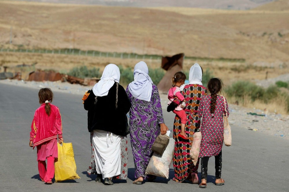 Women and children from the minority Yazidi sect, fleeing the violence in the Iraqi town of Sinjar, walk to a refugee camp.