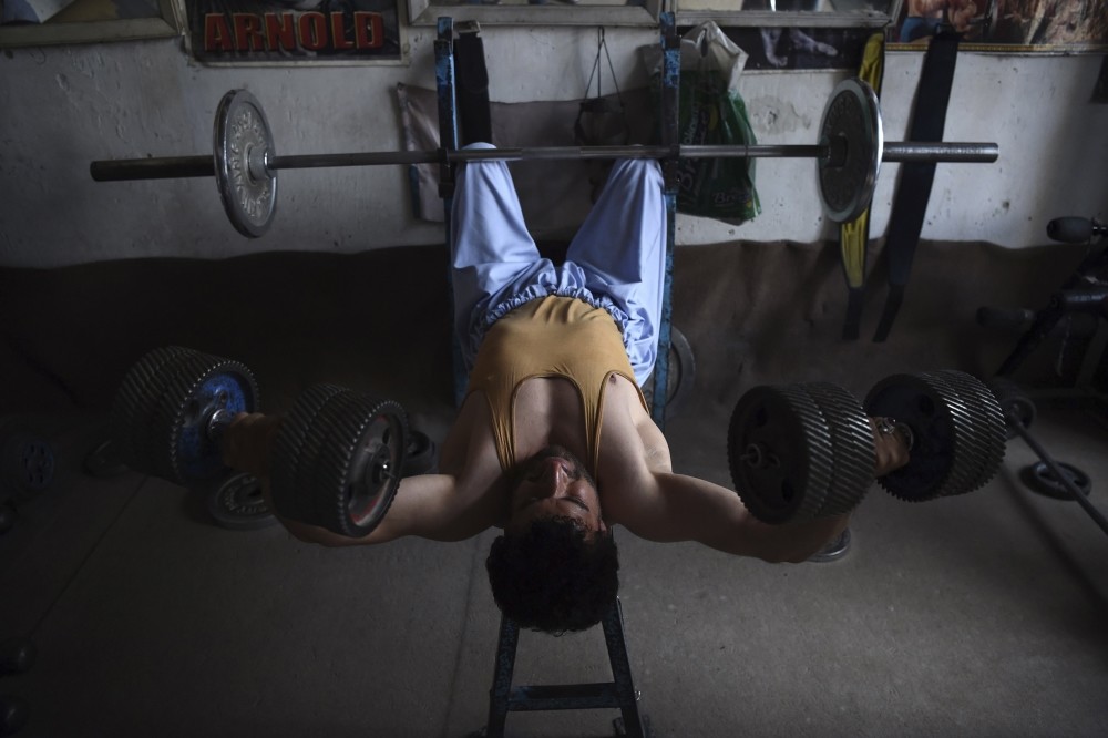 An Afghan bodybuilder exercises using dumbbells made from spare car parts.
