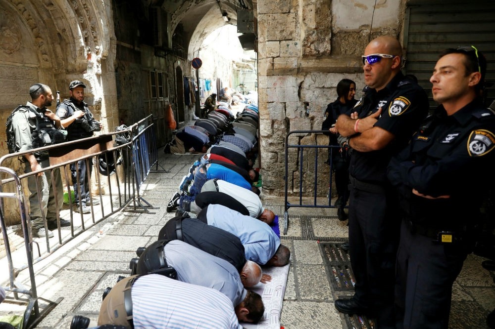 Palestinian men pray as Israeli security forces secure the Al-Aqsa mosque compound in Jerusalem's Old City, July 26.