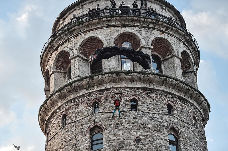 Turkish extreme sports athlete Cengiz Kocak performs a base jump off Galata Tower in Istanbul on November 9, 2017, as part of the events organised by European Outdoor Film Tour (EOFT) in Istanbul (AFP Photo)