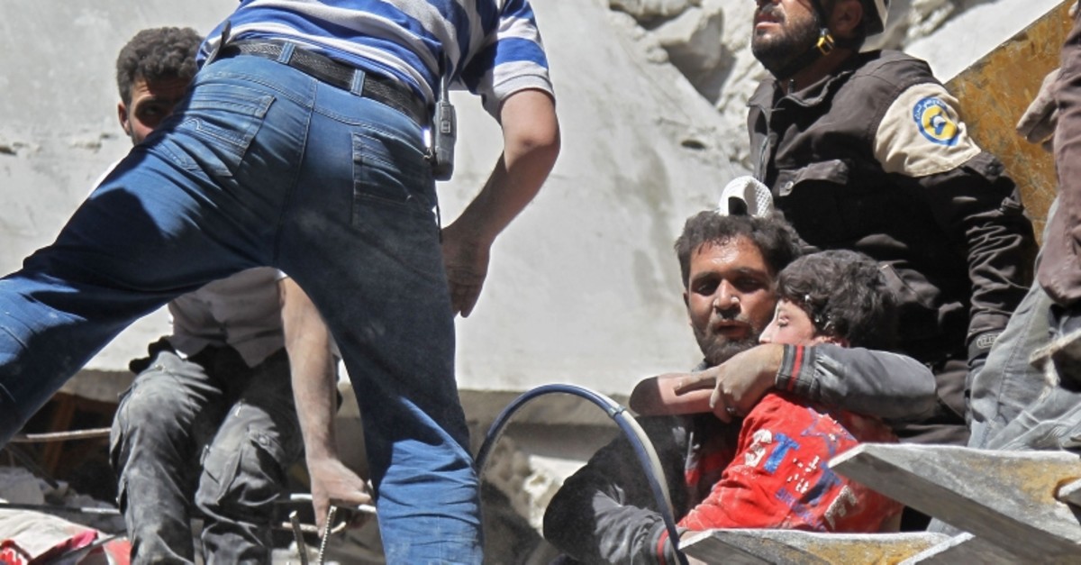 White Helmets rescue a child from the rubble of a building destroyed during an air strike by Assad regime forces on the town of Ariha, in the southern outskirts of Syria's Idlib province on May 27, 2019. (AFP Photo)