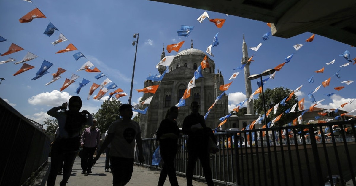 People walk beneath the flags of the ruling Justice and Development Party (AK Party), in Istanbul, June 20, 2018.