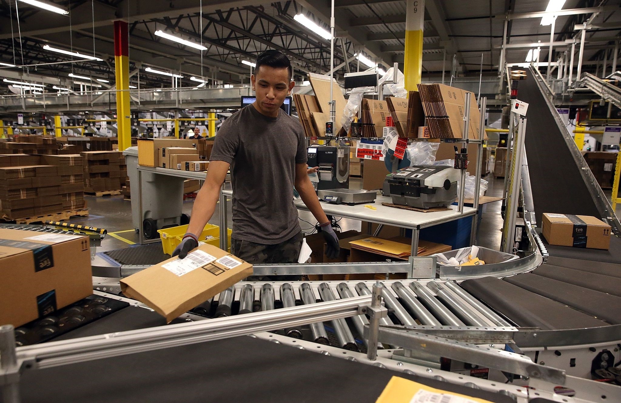 An Amazon.com worker sorts packages onto a conveyor belt at an Amazon fulfillment center in Tracy, California.