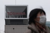 A woman walks in front of the logo of Japanese corportation Toshiba in Tokyo.