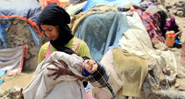 A displaced Yemeni girl holds her infant sister outside temporary shelters at a camp for Internally Displaced Persons (IDPs) on the outskirts of Sana'a, Yemen, 25 August 2018. (EPA Photo)