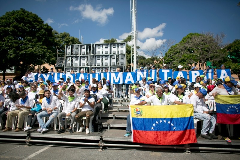 People holds a sign that reads in Spanish ,Humanitarian Aid, during an event to swear in nurses, doctors, professionals and others, as the group that will help with the distribution of humanitarian aid in Venezuela, Feb. 16, 2019. (AP Photo)