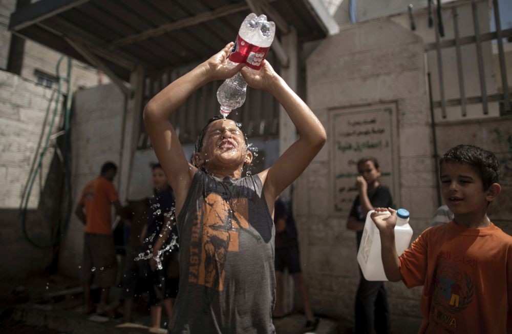 Two Gazan boys try to cool off by pouring bottles of water over their heads.