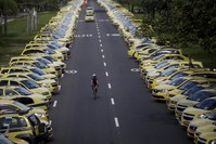 A man rides his bicycle between taxis parked on the street during a protest against the online ride-sharing service Uber in Rio de Janeiro, Brazil.