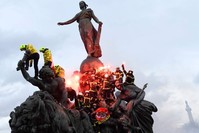Firefighters brandish flares as they climb on the Statue of Republic Triumph at Nation Square during a demonstration to protest against French government's plan to overhaul the country's retirement system in Paris, Jan. 28, 2020. (AFP Photo)