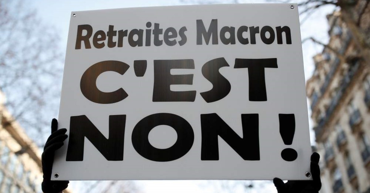 A demonstrator holds a placard which reads ,No to Macron's pensions reform, during a demonstration against French government's pensions reform plans in Paris as part of another day of nationwide strikes and protests in France, Jan. 24, 2020. (REUTERS)